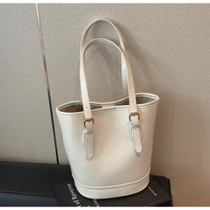 Detail view of cream bucket bag showing high-quality synthetic leather and gold hardware