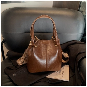 Detail of vintage brown bucket bag with textured leather and ethnic pattern wide strap