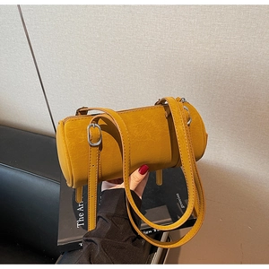 Detail of mustard yellow barrel bag featuring vintage crackle leather and silver buckles