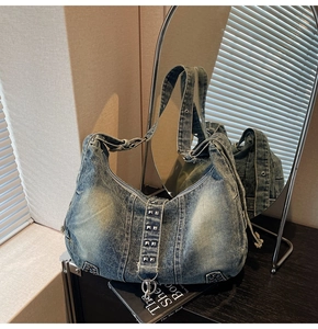 Close-up of washed blue denim hobo bag with silver square metal studs and zipper
