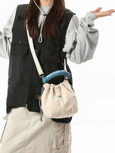Minimalist cream drawstring bucket bag with blue padded handles and casual tote style