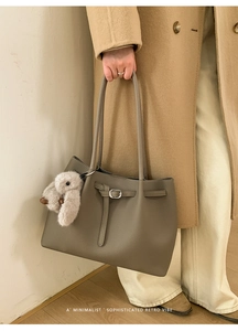 Detail of taupe leather tote bag featuring pebble texture and a cute rabbit charm