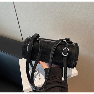 Detail of black cylindrical crossbody bag featuring textured leather and silver buckle