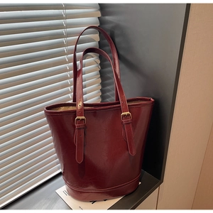 Macro detail of wine red leather texture and golden buckle on minimalist bucket bag