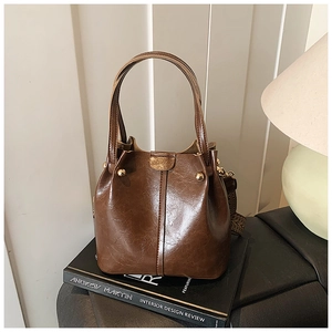 Close-up of vintage brown bucket bag with wide woven strap and gold metal accents