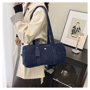 Detail view of deep blue denim cylinder shoulder bag showing texture and silver buckles