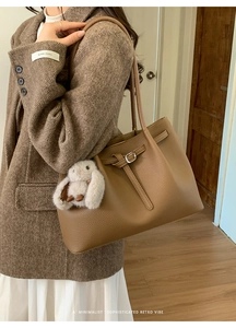 Detail of retro caramel brown leather tote bag with a white rabbit charm on side view