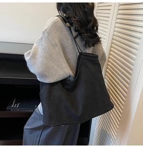 Detail view of large black suede tote bag showing soft draping and shoulder strap