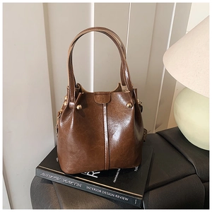 Detailed view of brown leather bucket bag with gold rivets and vintage stitching