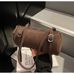 Close-up of brown cylindrical leather bag with adjustable straps and zipper detail