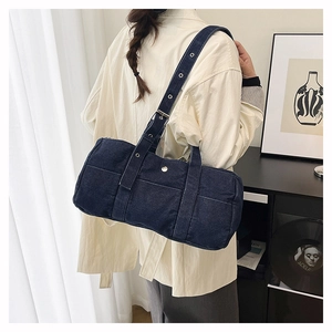 Detail of blue denim hobo bag with adjustable eyelet strap on model shoulder