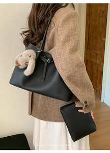 Close-up of black litchi grain tote bag with rabbit charm and inner pouch detail