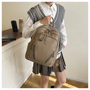 Litchi texture khaki backpack with dual zippers and ball pendant on model