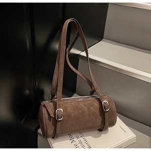 Detail of vintage brown cylinder bag with distressed leather texture and silver buckles