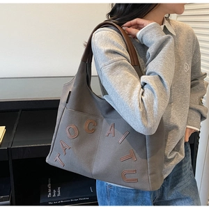 Close-up of a large capacity canvas tote bag in dark grey with brown leather letters