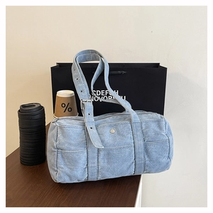 Detail of light blue denim tote bag showing washed texture and adjustable strap buckle