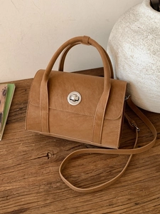 Vintage brown matte crossbody bag with silver buckle on a wooden table setup