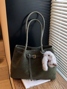 Olive green vintage tote bag with plush rabbit charm and gold buckle on a wood desk