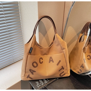 Close-up of khaki canvas tote with TAOCAITU leather patch and brown handles