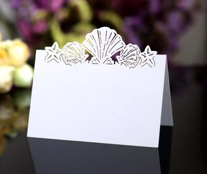 Detail of laser-cut white table card featuring ocean shell and starfish patterns
