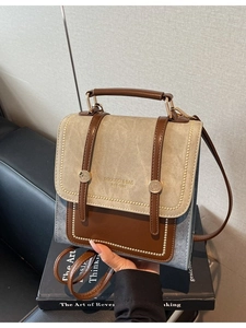 Retro square tote bag in blue denim and brown leather on a vintage leather sofa