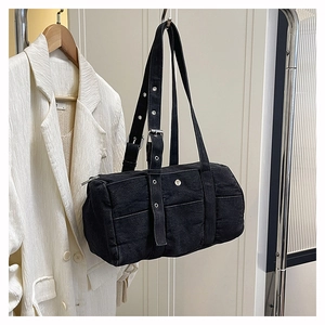 Detail of black denim barrel bag with eyelet straps styled on a metal hanger with a blazer
