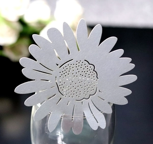 Macro shot of laser-cut white daisy paper place card on a wine glass rim