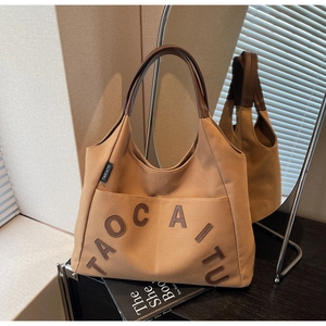 Detailed view of camel canvas tote bag with brown leather handles and brand logo tag
