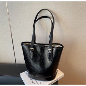 Detail view of the glossy black cracked leather bucket bag with metallic buckle