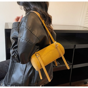Detail of ginger yellow cylindrical barrel bag with silver buckle and dual straps
