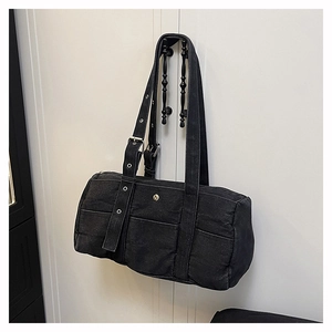 Detail of black washed canvas cylinder tote bag with contrast stitching and metal eyelets