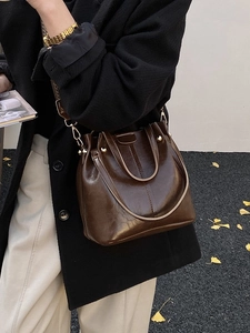 Vintage dark brown bucket bag with wide woven strap and polished gold hardware detail