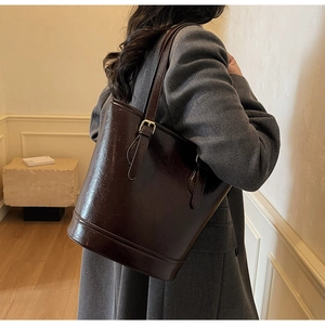 Detailed view of large dark brown bucket bag in polished leather with adjustable strap