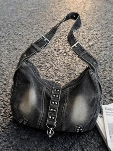 Vintage washed black denim hobo bag with silver metallic studs on a street pavement