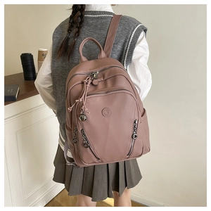 Detail of pink faux leather backpack with litchi texture and metal bell pendant decoration