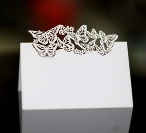 Elegant white laser-cut butterfly wedding place cards with intricate hollow floral patterns