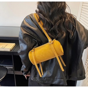 Detailed view of yellow cylindrical crossbody bag with vintage leather texture and silver buckle