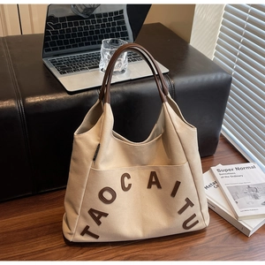 Detail of cream canvas tote with leather handles and large front pocket on a bench