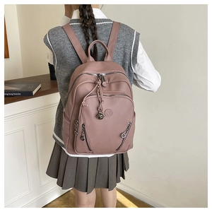 Side view of a pink pebbled leather backpack for women with multiple zipper pockets