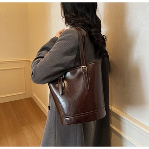 Detail view of coffee brown faux leather tote with vintage texture and gold buckle hardware