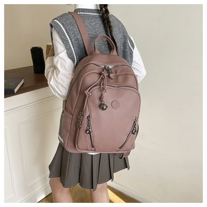 Close-up of a pink leather backpack with zipper details and metallic ball pendant