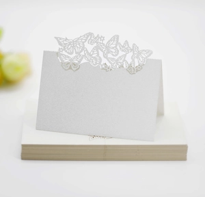 Detail of white laser-cut butterfly place cards with pearl finish for wedding table decor