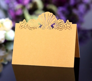 Close-up of laser-cut gold pearlescent table card with shell and starfish patterns