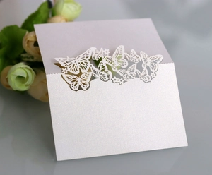 Detail of white laser-cut butterfly place cards with a subtle pearlescent shimmer finish