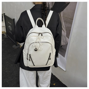 Detail view of a white pebble grain backpack showing layered zippers and hanging charms