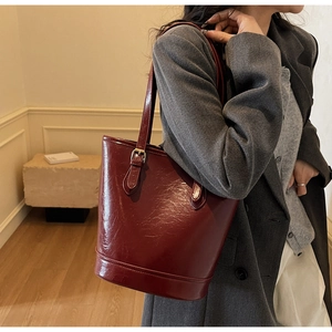 Detail of burgundy leather bucket bag with gold hardware and fine shoulder strap
