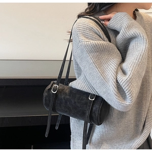 Detail of vintage matte leather cylinder bag with double straps and silver buckles