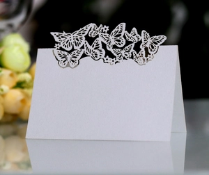 Macro detail of laser-cut butterfly wedding place cards with heart pattern on premium paper