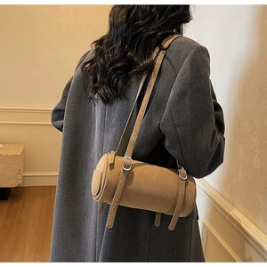 Detail view of stylish beige cylinder shoulder bag with adjustable double straps for women