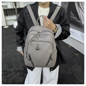 Close-up of gray pebble leather backpack with decorative metal charms and side pockets